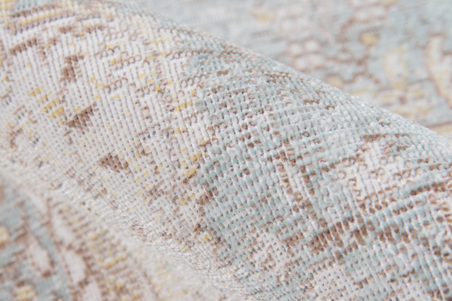 Close-up of a textured woven rug in beige, pale blue and brown tones with an abstract pattern.