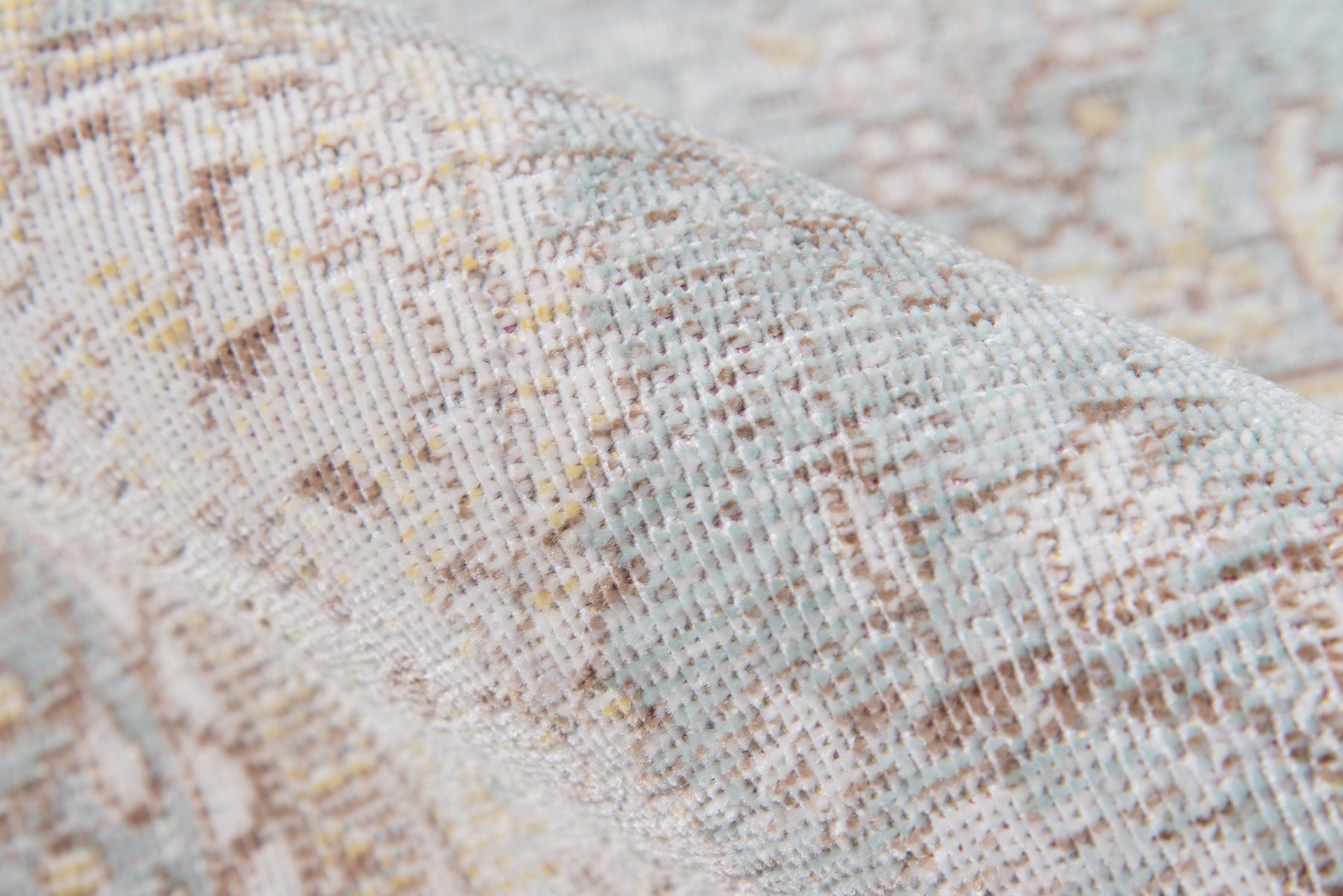 Close-up of pastel woven rug in beige, light blue and tan with a textured, soft pattern.