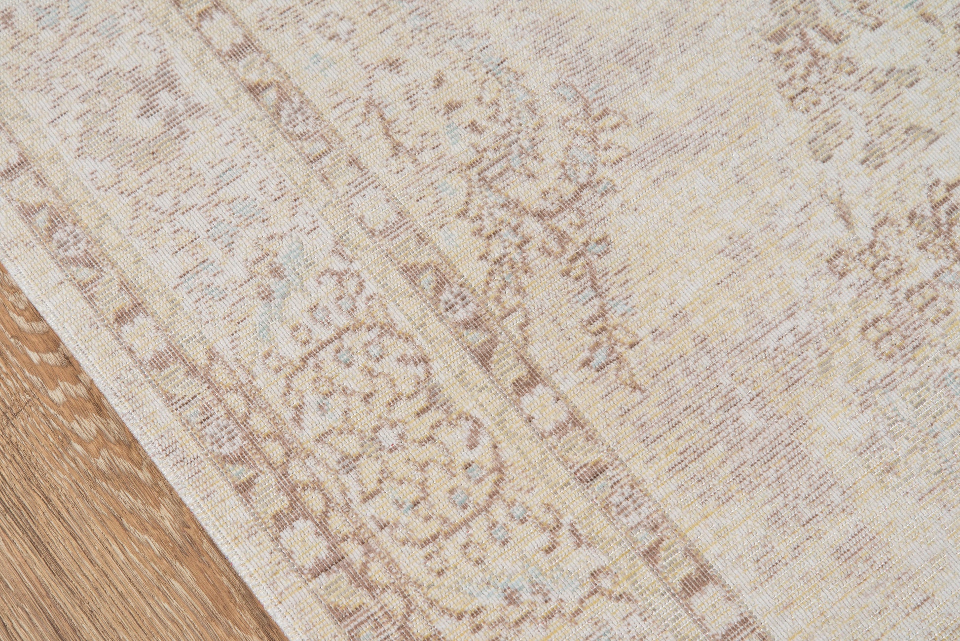 Ivory beige oriental rug with muted floral border on a wooden floor.