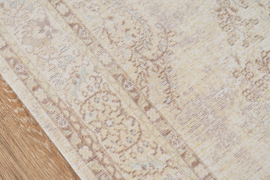 Cream and beige vintage-style rug with muted floral border on a wooden floor.