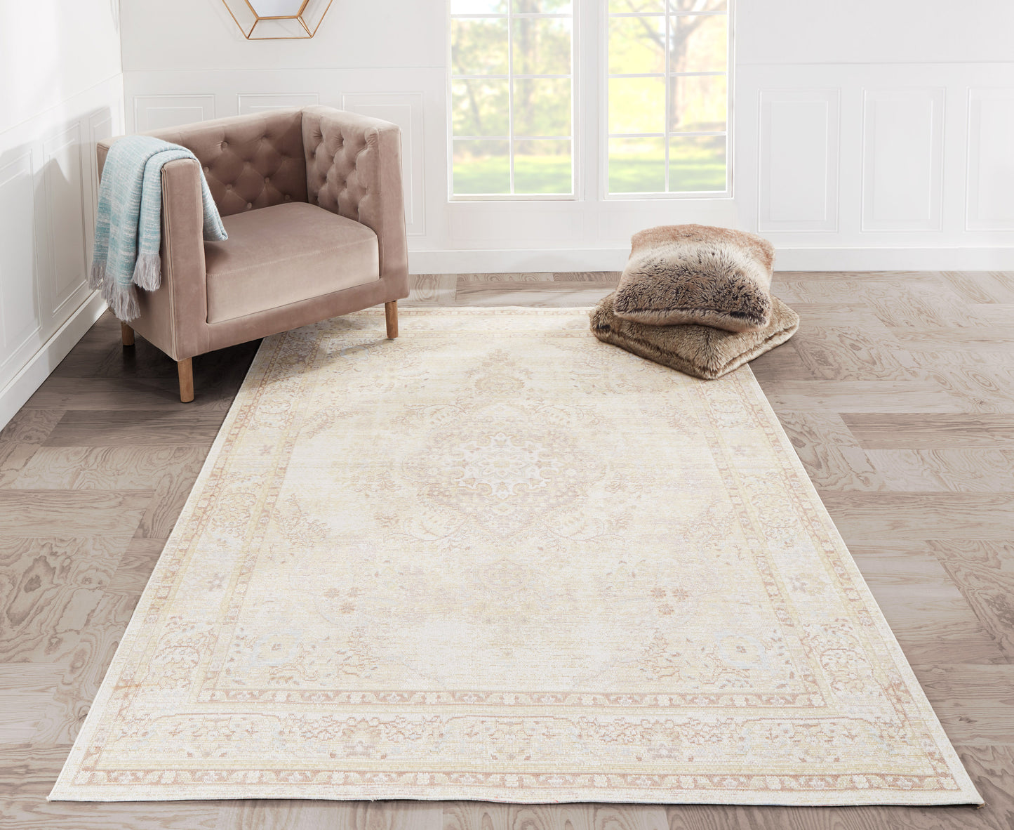 Rectangular cream area rug with subtle ivory border, in a bright living room beside a blush tufted chair and cozy throw.