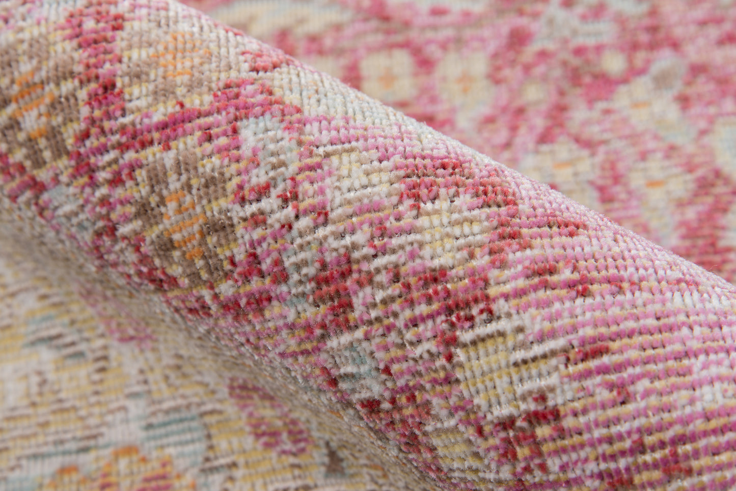 Pink, cream, and beige woven rug with floral pattern, rolled up for display; textured home decor.