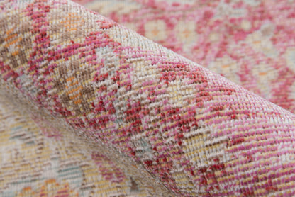 Pink, cream, and beige woven rug with floral pattern, rolled up for display; textured home decor.