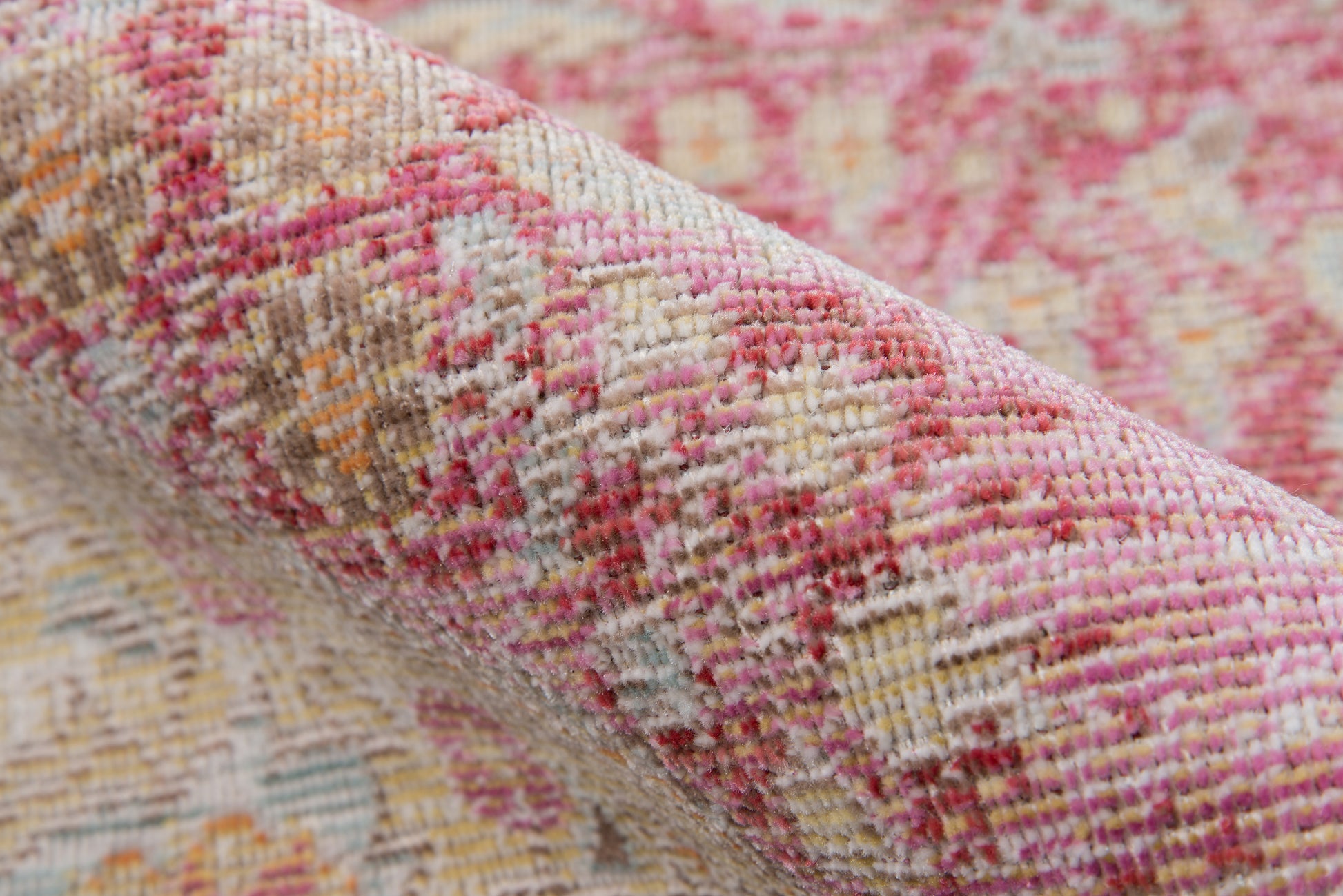 Close-up of pink, cream & orange woven rug with floral geometric pattern and soft textured fibers.