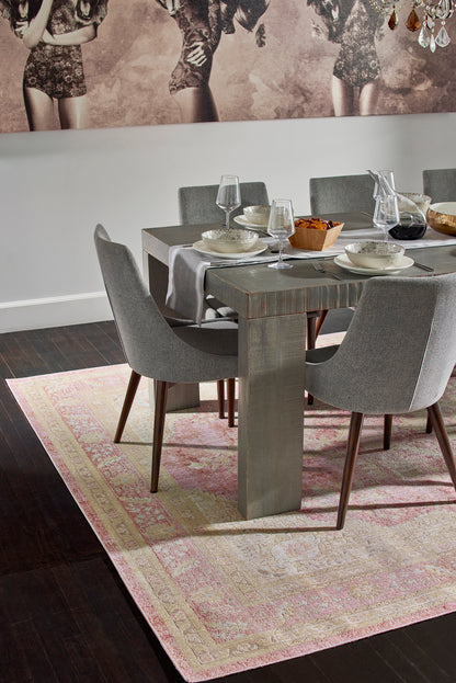Grey patterned rug with pink accents beneath a dining table and grey upholstered chairs.