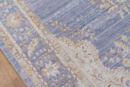 Blue and beige oriental rug with cream floral border, partially visible on a wooden floor.
