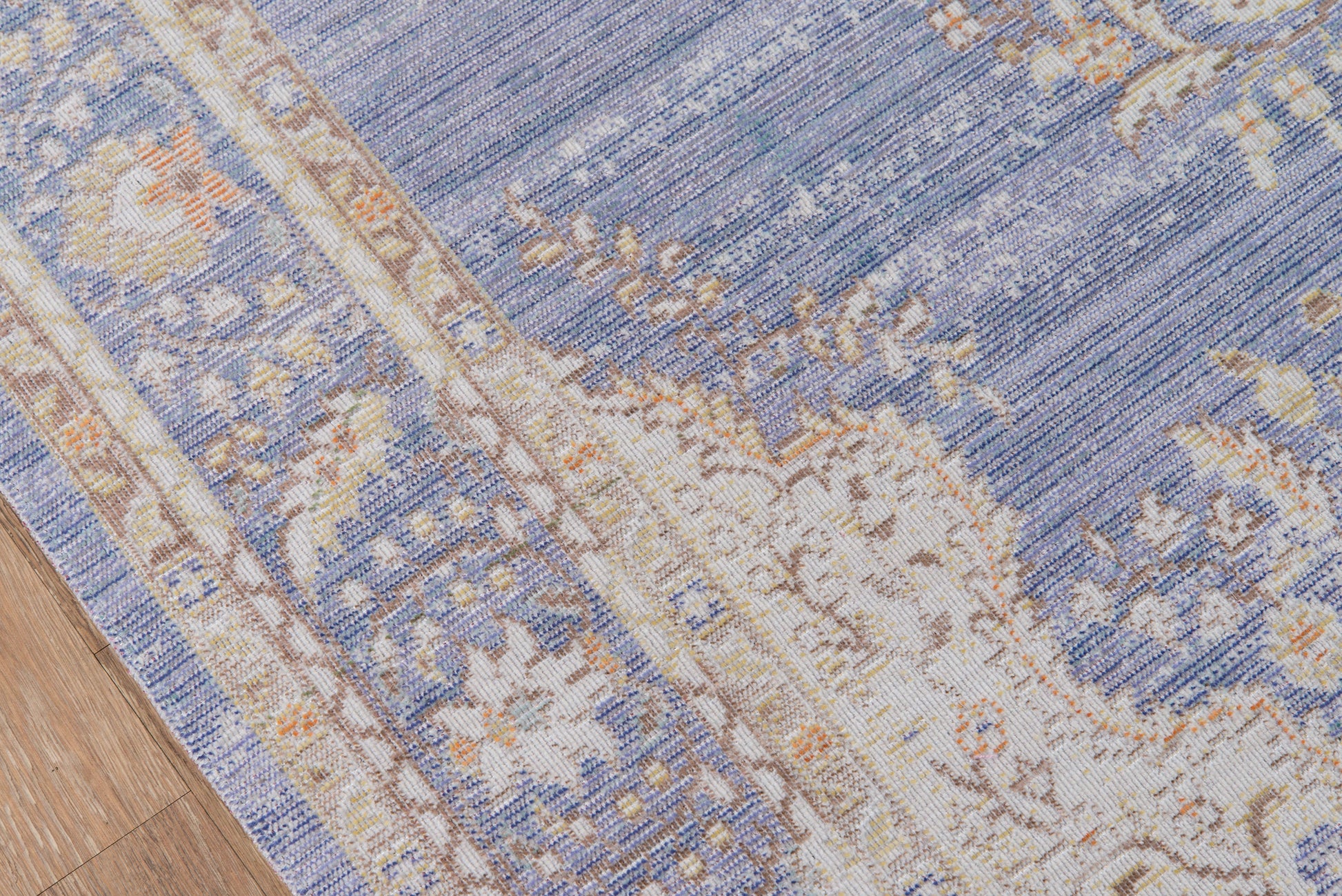 Blue and ivory ornate oriental runner rug with floral border on wooden floor.