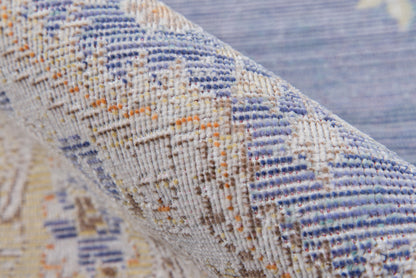 Woven geometric rug with blue, beige and orange accents, textured fabric shown folded.