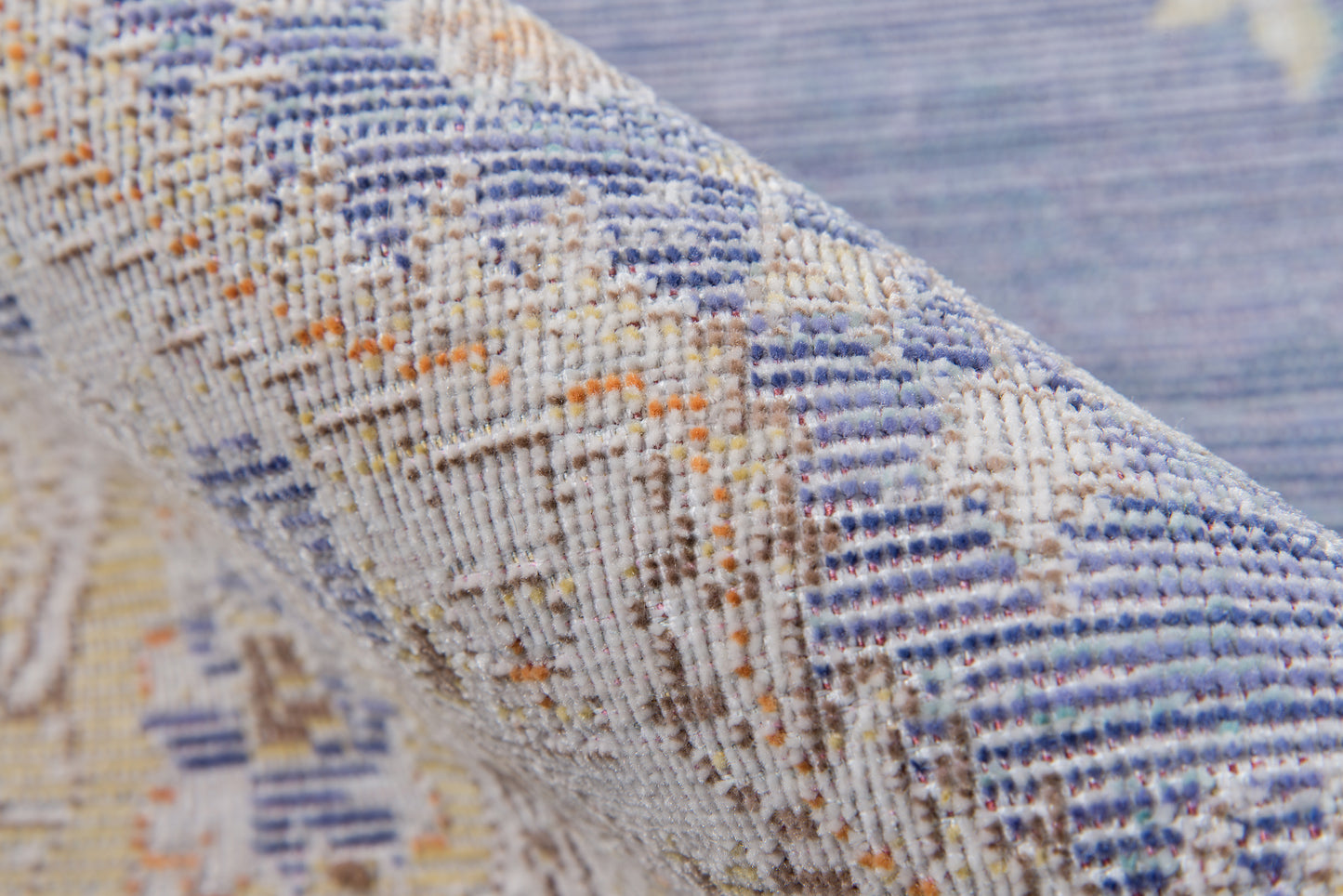 Close-up of blue and beige woven rug with geometric ikat pattern and orange accents.