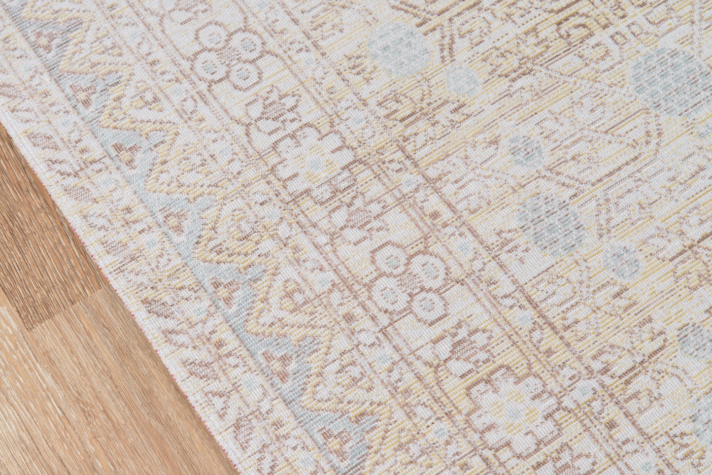 Blue and ivory woven rug with floral and geometric motifs on a wooden floor.