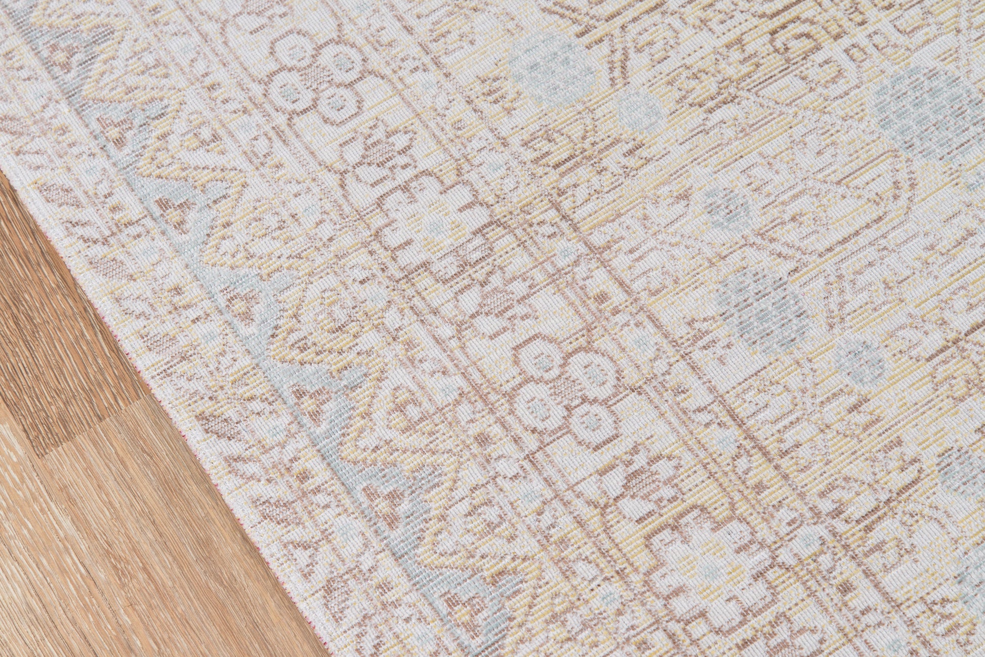 Blue and ivory woven rug with floral and geometric motifs on a wooden floor.