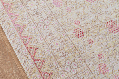Beige oriental-style area rug with pink floral motifs on a wooden floor; vintage-inspired pattern.