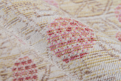Close-up of a woven beige rug with pink floral motifs, soft textured fabric, vintage-style decor rug.
