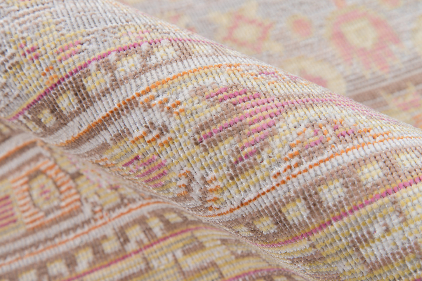 Close-up of a pastel geometric woven rug with pink, orange, cream tones; kilim-style bands and textured loom weave.