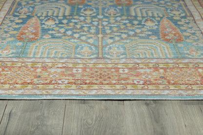 Blue oriental rug with cream floral motifs and a rust-red border on gray wood floor.