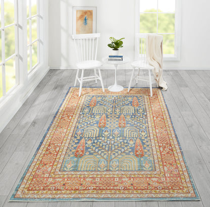 Rectangular oriental-style rug in blue, gold and coral with intricate border, in a white living room with two white chairs.