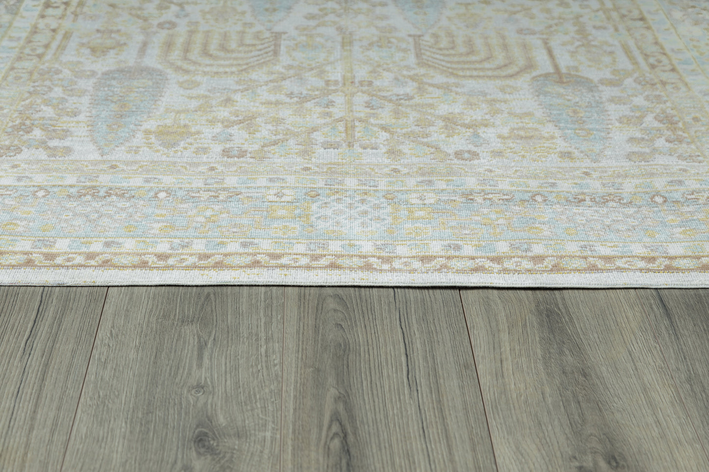 Ivory runner rug with a pale blue & beige floral motif on a gray wooden floor.