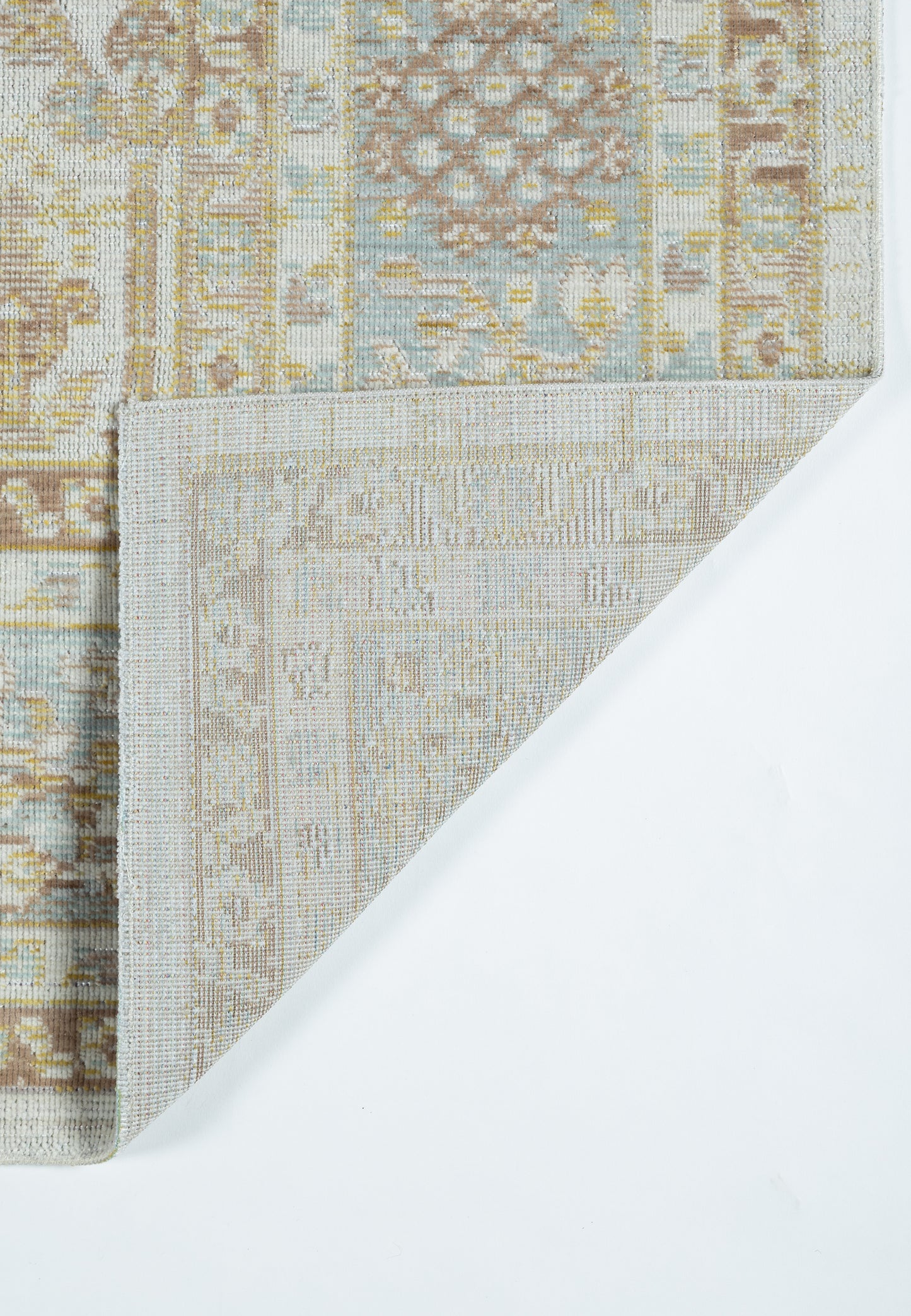 Pastel beige and blue patterned rug with geometric motif, folded corner reveals lighter underside.