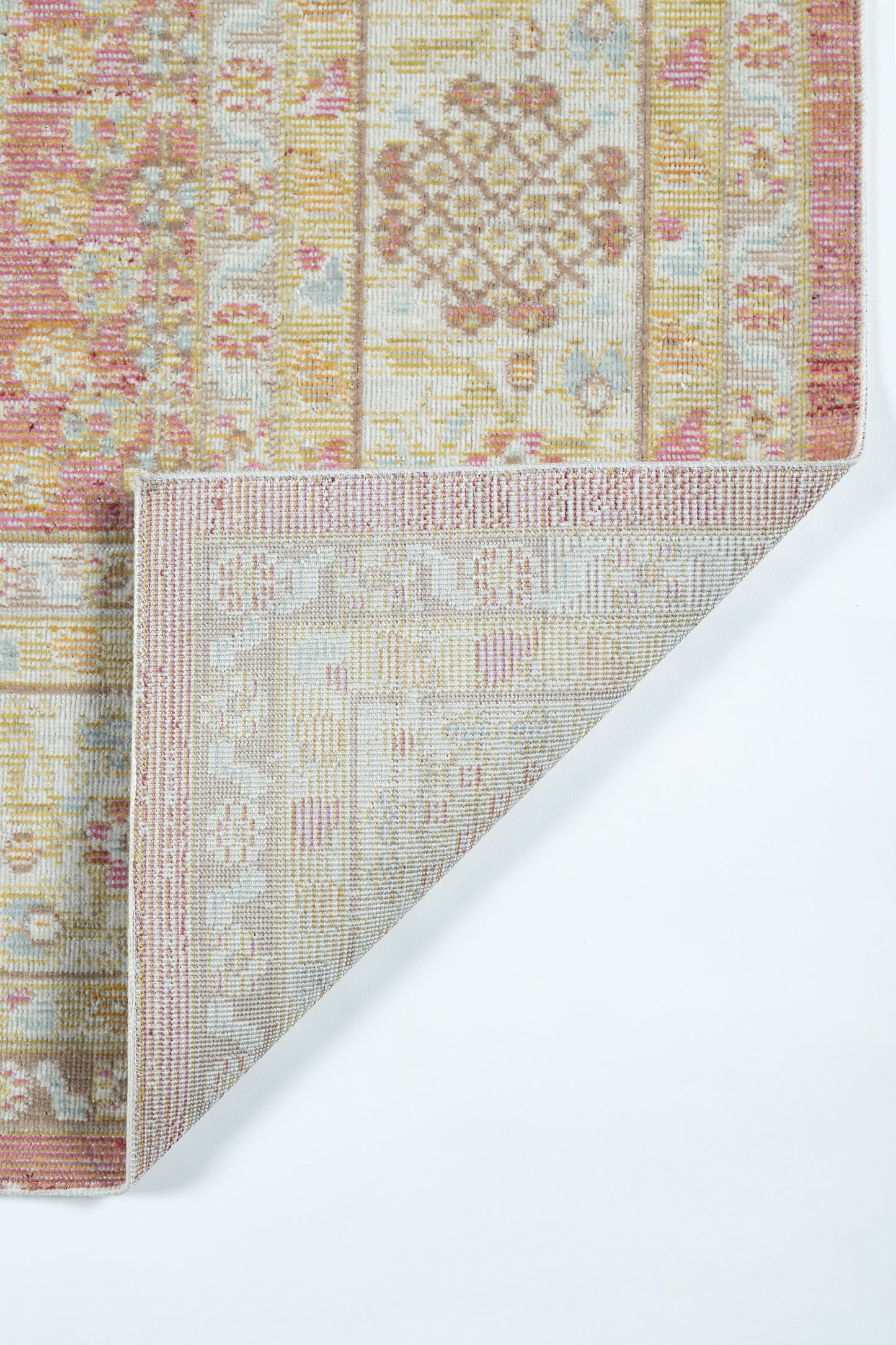 Pink and beige oriental rug with gold accents; ornate geometric motifs, folded corner reveals light beige underside.