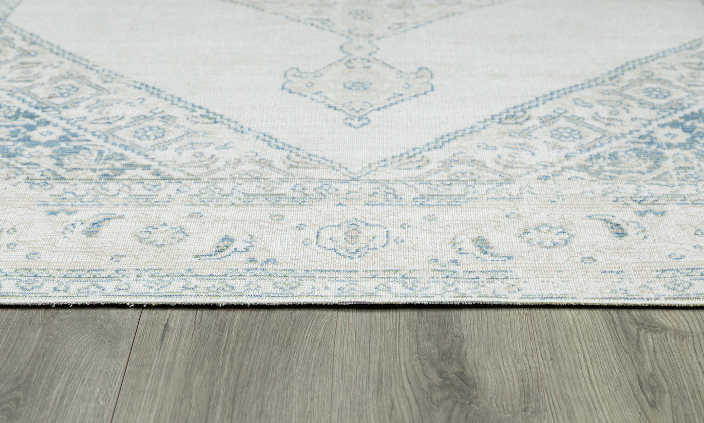 Pale blue and ivory oriental rug with floral border, laid on a wood floor.