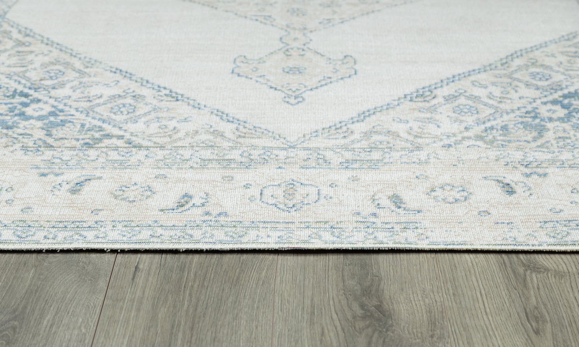 Pale blue and ivory oriental rug with floral border, laid on a wood floor.