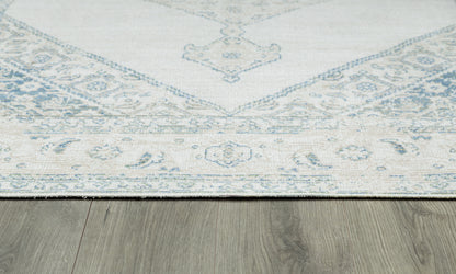 Pale blue and ivory oriental rug with floral border, laid on a wood floor.
