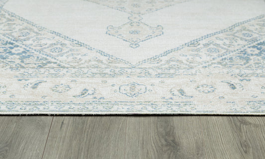 Light beige rug with faded blue oriental pattern and floral border on gray wooden floor.
