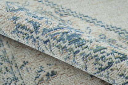 Blue, beige and green geometric woven rug with a rolled edge, perfect for living room decor.