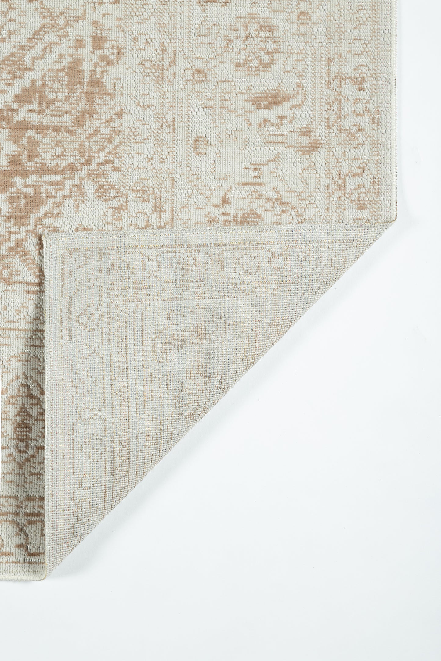 Beige-brown Oriental-style rug with faded floral pattern; woven texture, folded corner showing underside.