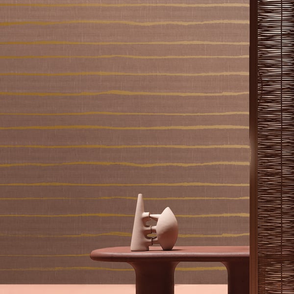 White ceramic abstract cone and orb sculpture on a brown oval table, striped wall with a woven screen.