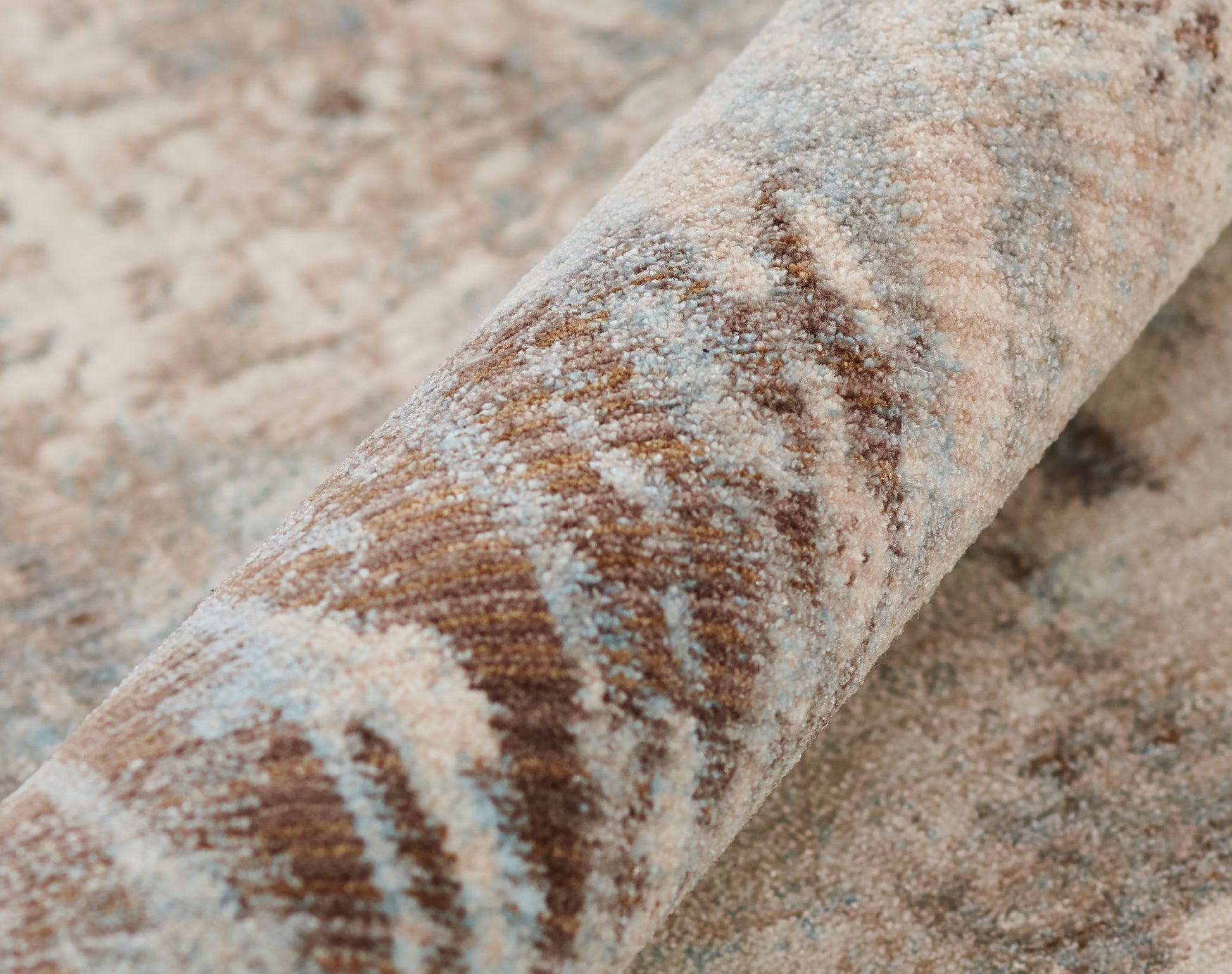 Rolled oriental-style rug in brown, beige and dusty blue with a distressed pattern and plush pile.