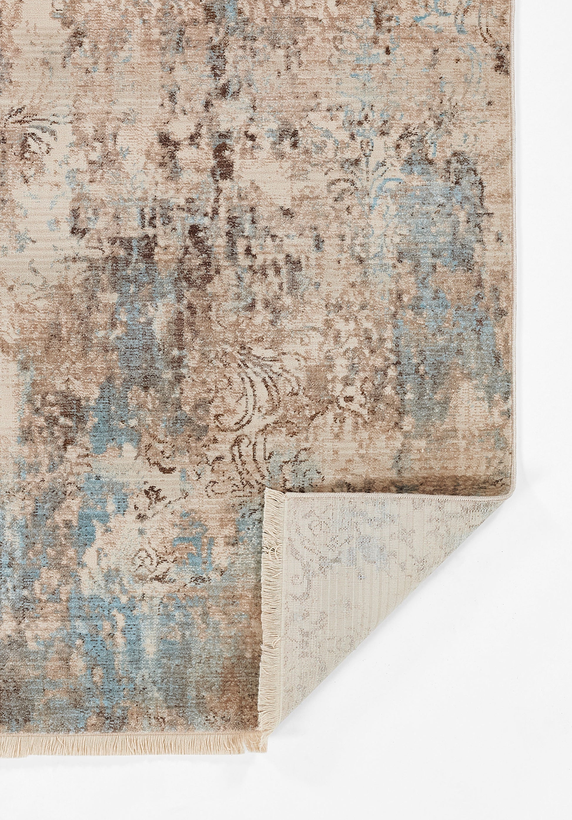 Distressed beige and blue vintage-style rug with floral pattern; folded corner shows the backing.