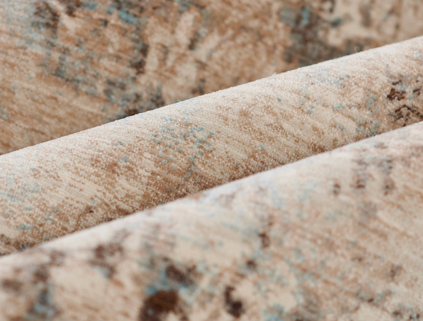 Close-up of beige oriental rug with blue accents, woven pile, folded edge.