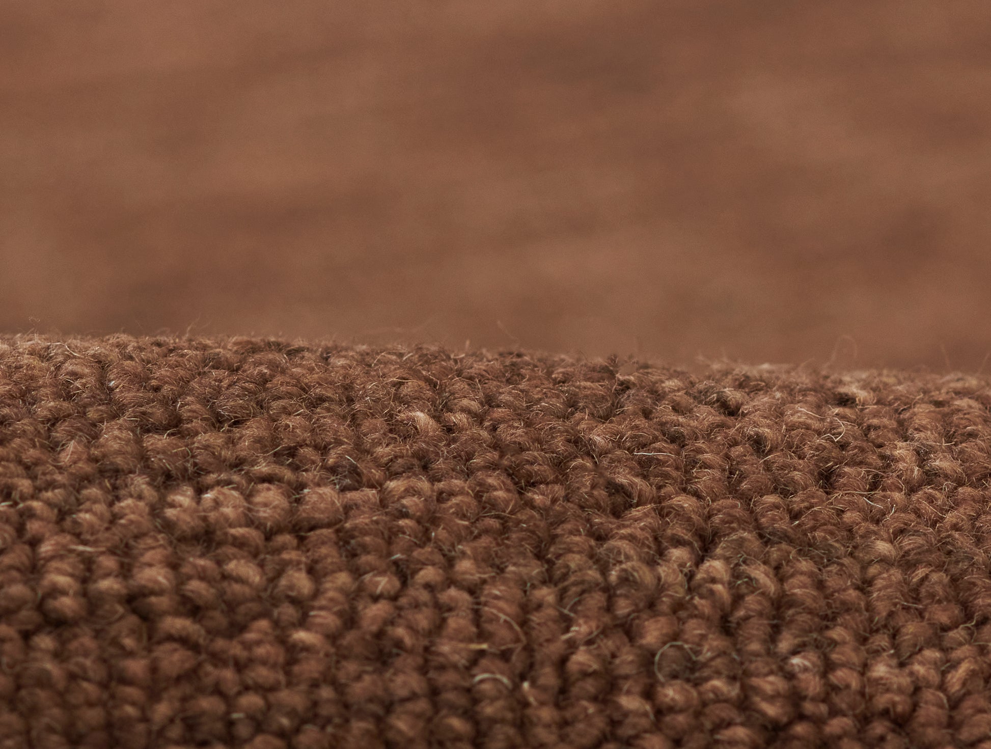 Close-up of brown loop-pile rug fibers in warm chocolate brown; dense, textured.