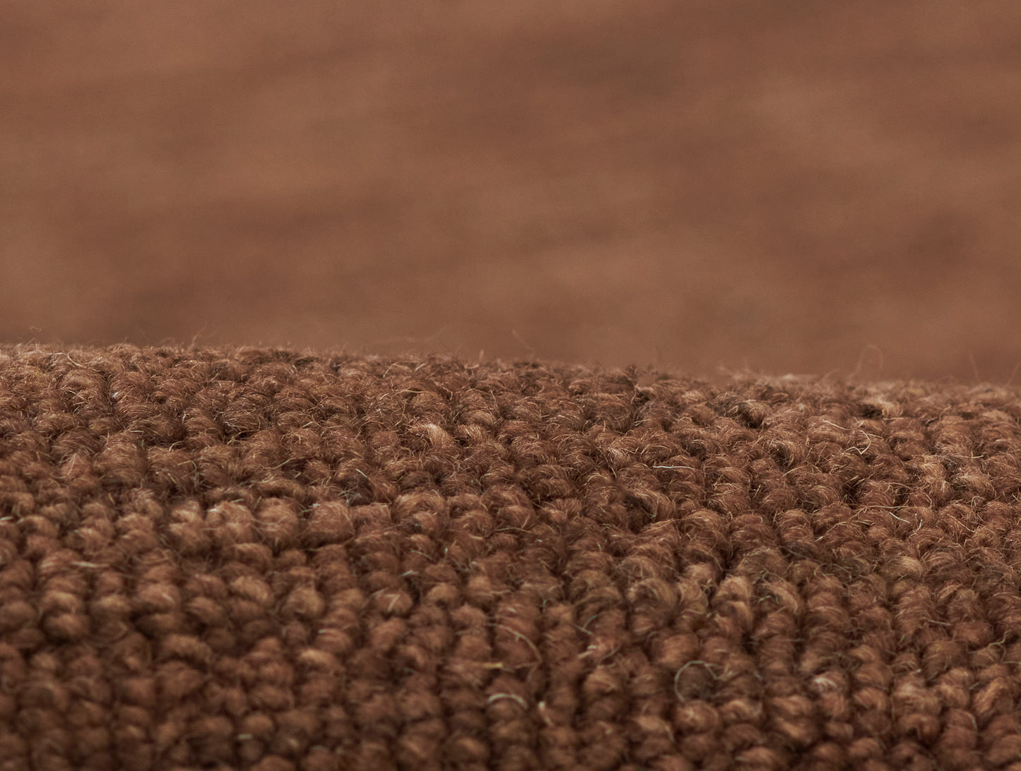 Brown loop-pile rug close-up; dense textured fibers for cozy living room flooring.