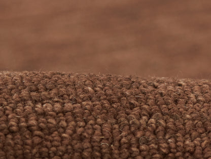 Brown loop-pile rug close-up; dense textured fibers for cozy living room flooring.