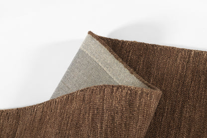 Brown textured rug with soft boucle pile and light gray backing; close-up fabric detail.