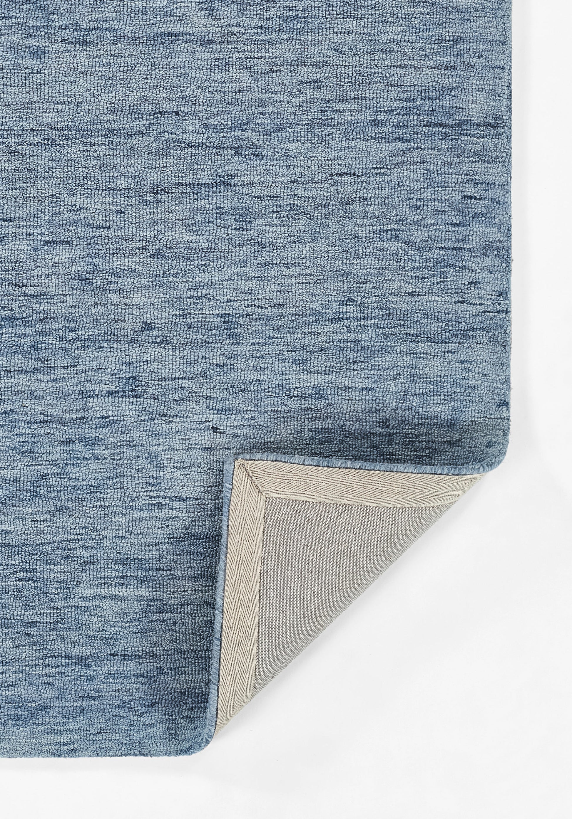Blue heathered fabric rug with a folded corner revealing light beige backing and gray underside.