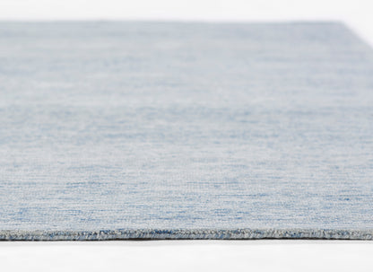 Light blue woven rug with subtle denim texture and gray binding edge.