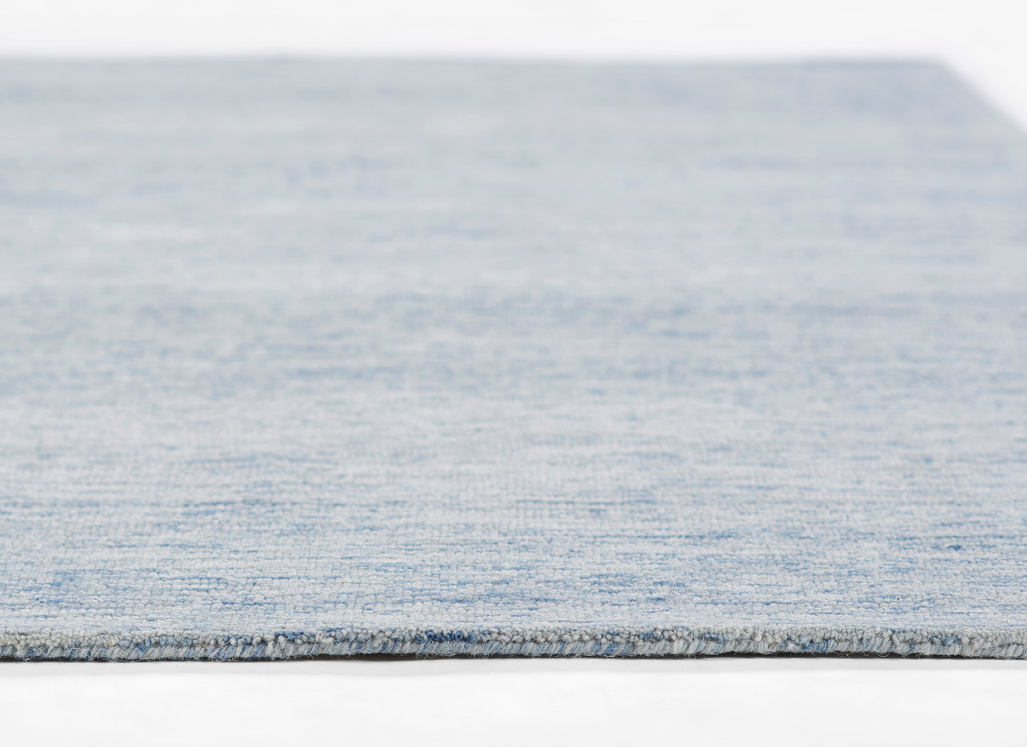 Blue denim flatweave rug with textured surface and light fringe along the edge.