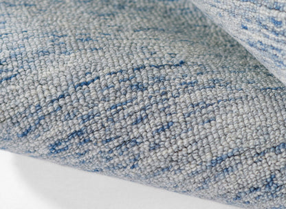 Close-up of a gray-blue woven area rug with a subtle blue speckled pattern and soft textured pile.