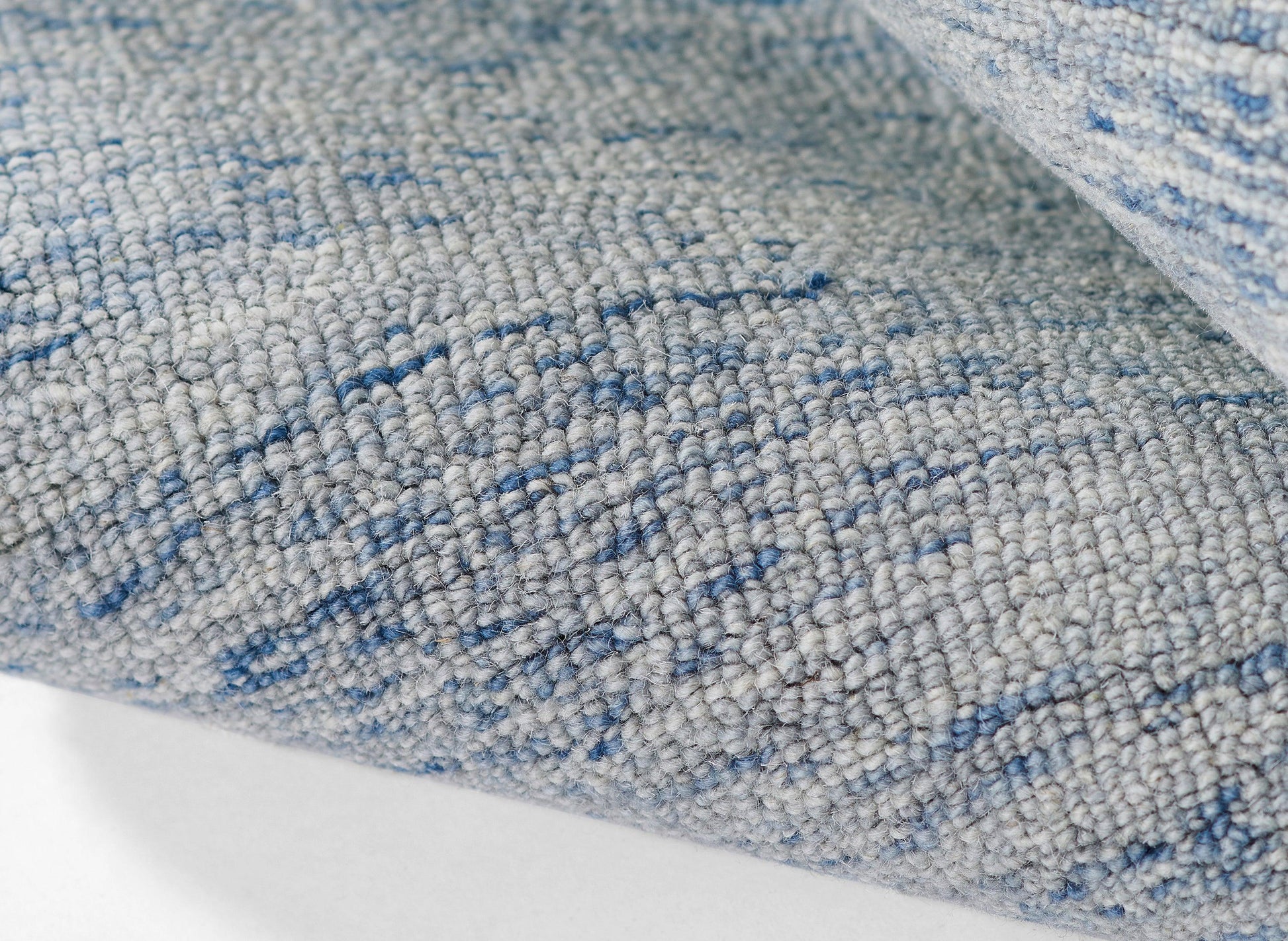 Blue-gray textured woven rug with a speckled pattern and rolled edge.