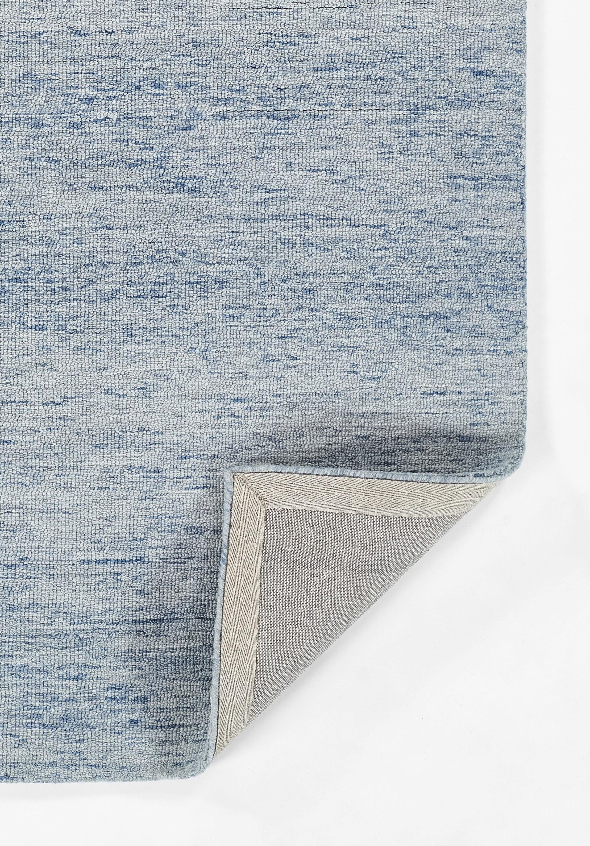 Blue heathered woven rug with beige underside, folded corner