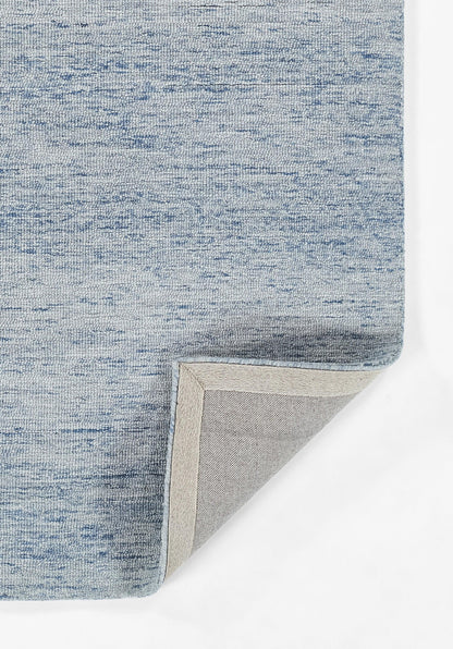 Light blue heathered rug with beige underside; corner folded to show stitched edge and soft pile.