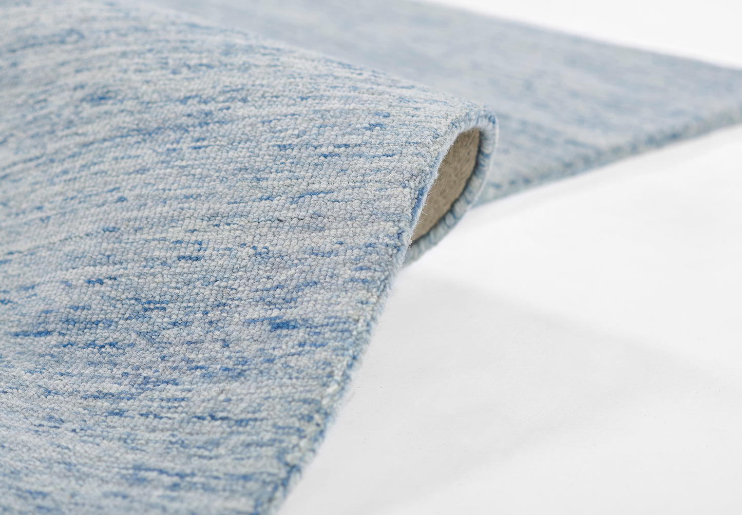 Light blue speckled woven rug, partially rolled edge, soft textured fabric, modern casual home decor accessory.