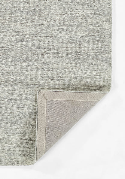 Grey heathered flat-weave rug with folded corner showing beige underside.
