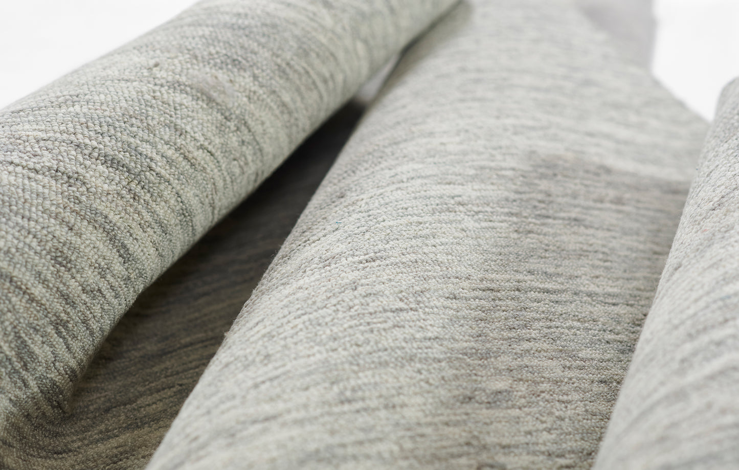 Close-up of light gray heather rug with soft texture and rolled folds.