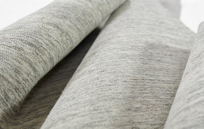 Close-up of light gray heather rug with soft texture and rolled folds.