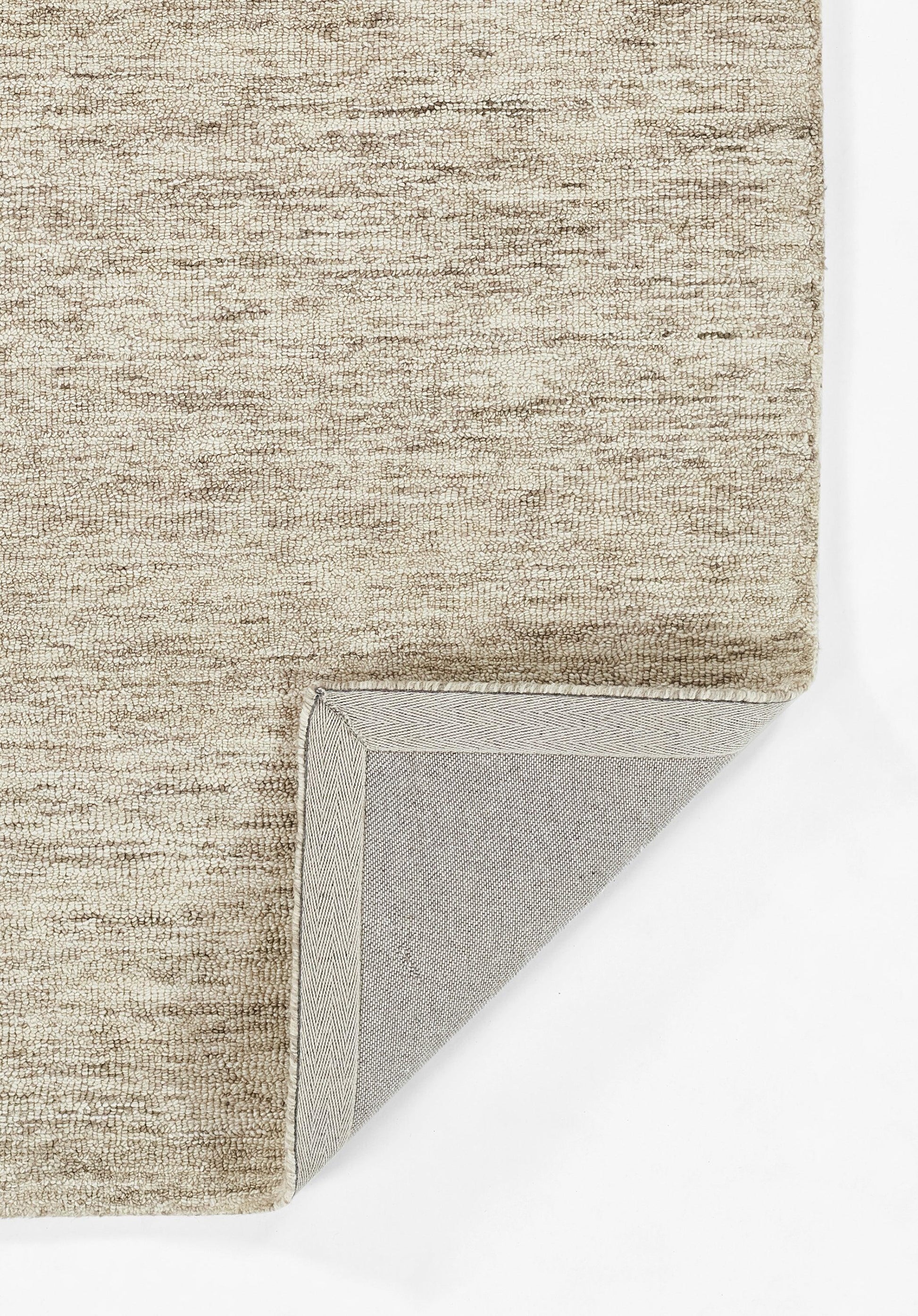 Beige textured rug in natural NAT color, folded corner reveals grey underside.