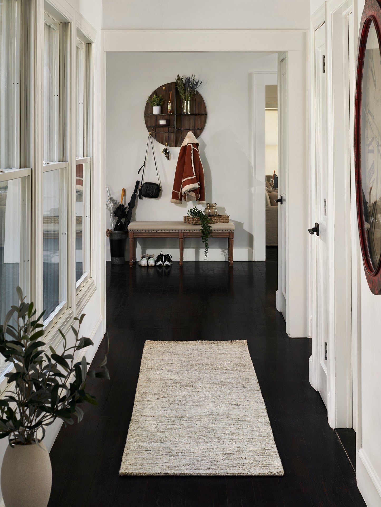 Natural beige woven rug in a white hallway with a dark wood floor and an entryway bench, 8' x 10'.